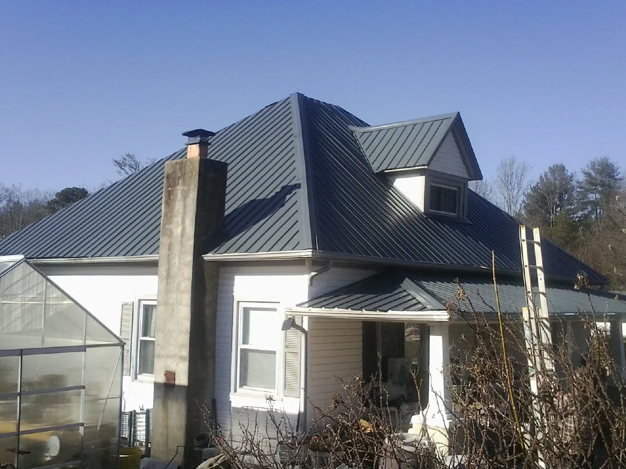 Dark blue standing seam metal roof on a white farmhouse with dormer — Slate & Tile Roof Repair by Roofing Brothers in Dulzura